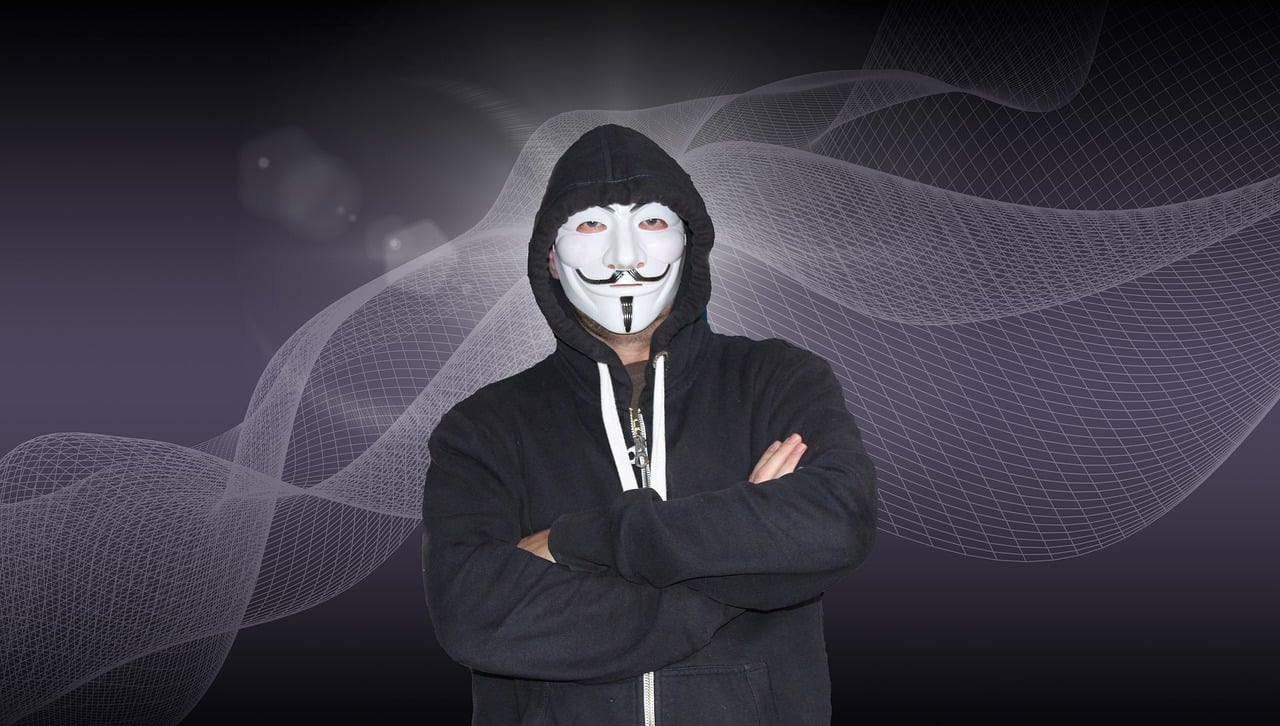 Masked presenter in a dark hoodie